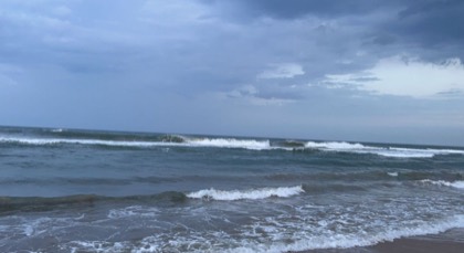 A grey overcast sea with waves breaking on an empty shore