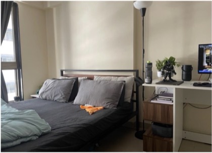A bedroom with a grey-linened bed, a desk with a monitor and a Black Panther figure on it