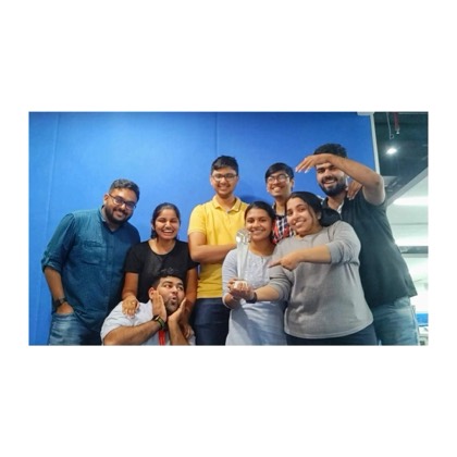 Eight colleagues crowded around a trophy against a blue backdrop