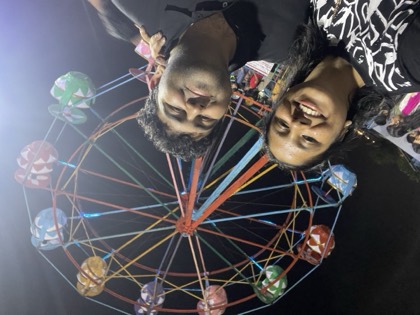 Tejas and Shreya smiling in front of a lit ferris wheel at night