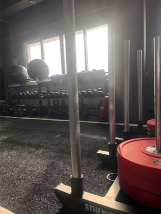 A loaded gym sled on a turf track, backlit by a row of windows