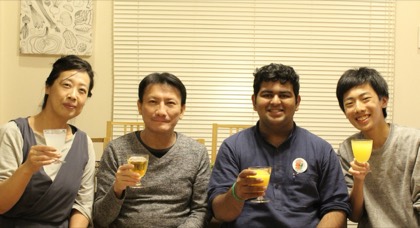 Tejas raising a glass at a table with his host family in Japan